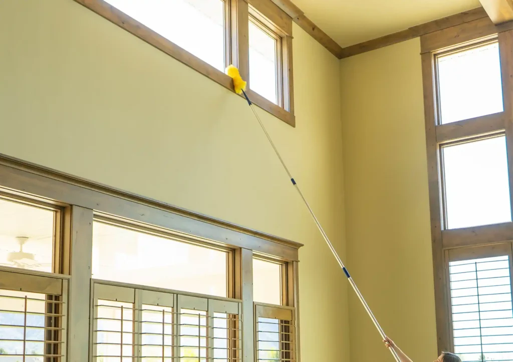 تنظيف الزوايا العالية والسقف في فيلا باستخدام عصا طويلة لإزالة الغبار